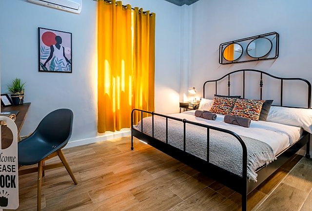 Private double room with a black iron bed and yellow curtains