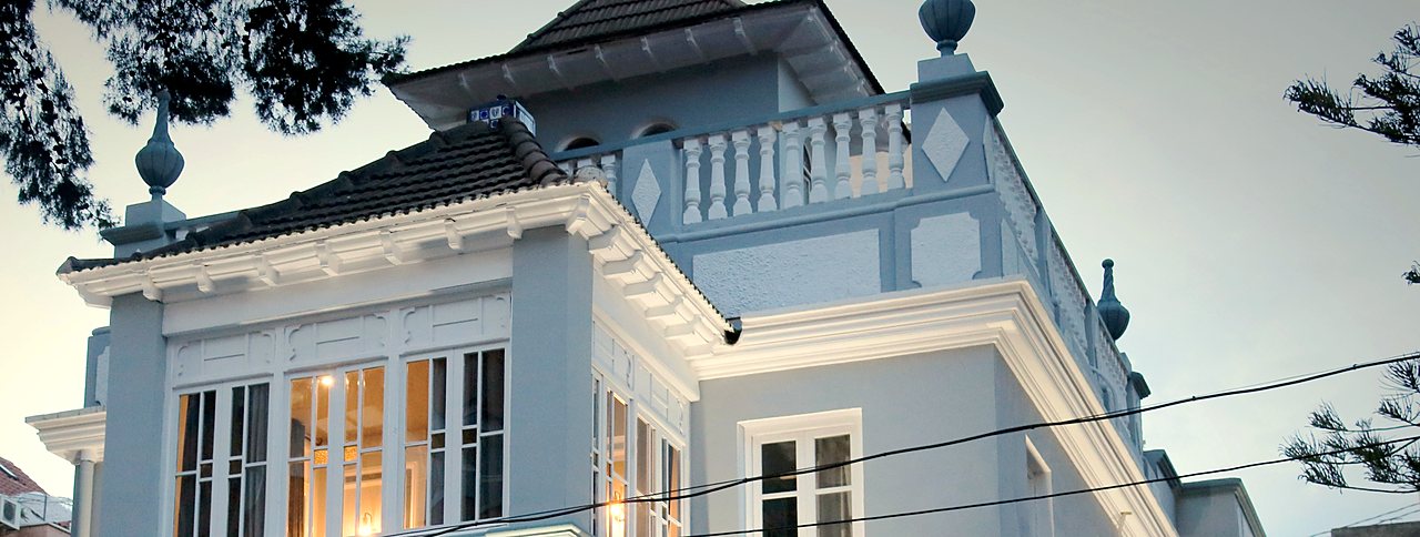 One of the partner hostels in Valencia: an old white villa with balconies, lit up at dusk