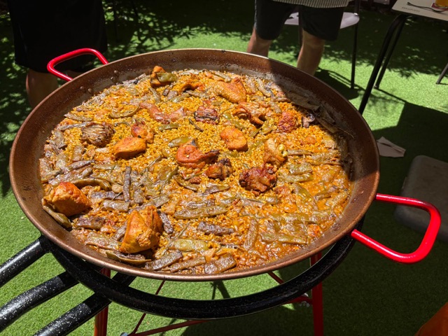 Finished paella valenciana with chicken and ferraura beans in a pan with red handles