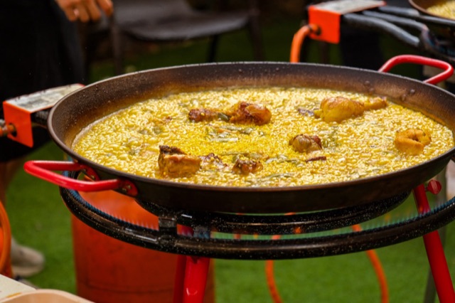Paella rice simmering on a gas paella burner with red legs